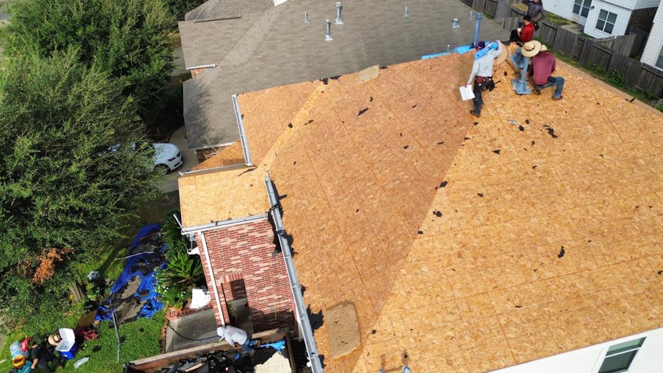 Roofing crew working on exposed roof decking