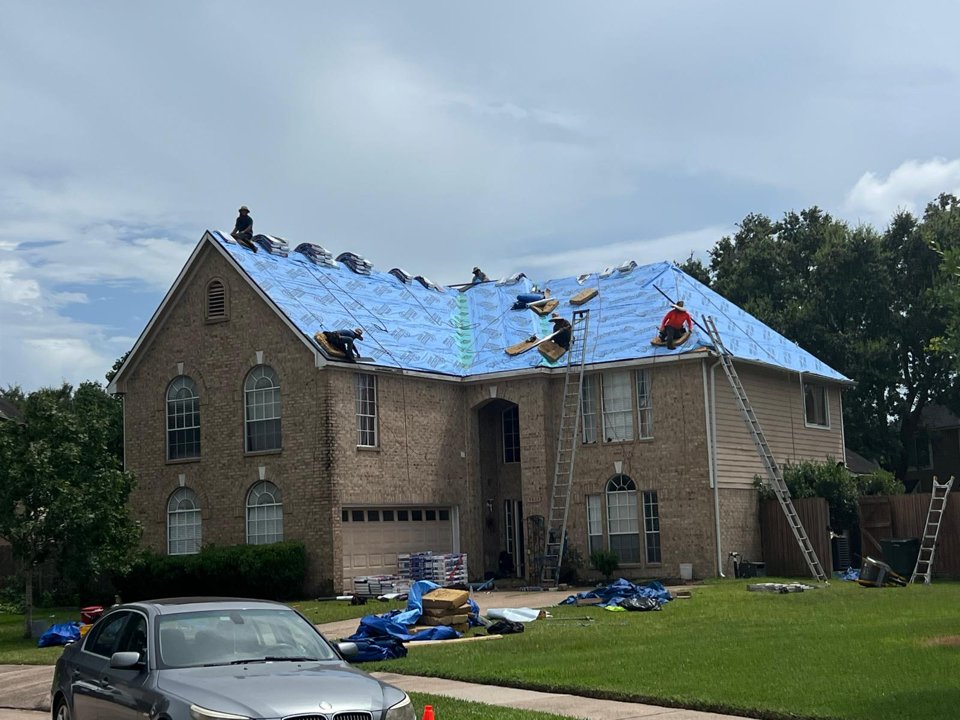 Roofing crew installing underlayment on a two-story home